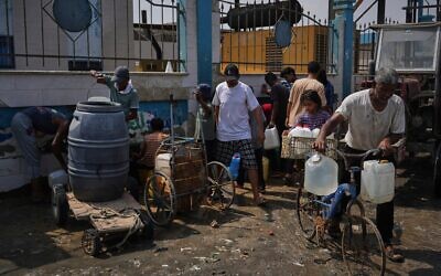 Des Palestiniens viennent chercher de l'eau potable dans une usine de dessalement à Deir al-Balah, dans le centre de la bande de Gaza, le 13 août 2025. (Crédit : AP Photo/Abdel Kareem Hana)
