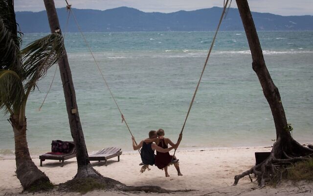 Illustration : un couple assis sur une balançoire suspendue à des palmiers sur une plage de l'île de Ko Pha Ngan. 15 août 2017. (Crédit : Nati Shohat/FLASH90)