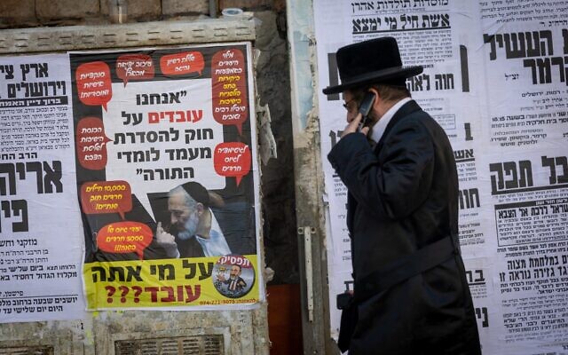Une affiche montrant le chef du parti Shas, Aryeh Deri, accompagnée du message : « Nous travaillons sur une loi visant à réglementer le statut des étudiants de la Torah », suivie de la question : « Qui essayez-vous de berner ? », dans un quartier ultra-orthodoxe de Jérusalem, le 28 octobre 2025. (Crédit : Chaim Goldberg/Flash90)