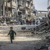 Un enfant gazaoui courant devant des bâtiments détruits pendant la guerre de Gaza, à Khan Younès, dans le sud de la bande de Gaza, le 6 novembre 2025. (Crédit : Abed Rahim Khatib/Flash90)