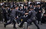 La police arrêtant un homme ultra-orthodoxe lors d'une manifestation contre l'enrôlement des Haredim dans l'armée israélienne, devant un centre de recrutement militaire, à Jérusalem, le 12 novembre 2025. (Crédit : Chaïm Goldberg/Flash90)