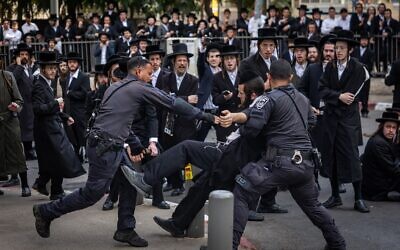 La police arrêtant un homme ultra-orthodoxe lors d'une manifestation contre l'enrôlement des Haredim dans l'armée israélienne, devant un centre de recrutement militaire, à Jérusalem, le 12 novembre 2025. (Crédit : Chaïm Goldberg/Flash90)