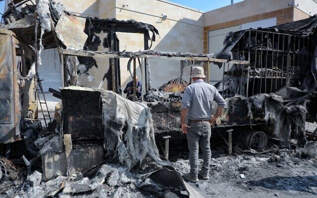Un homme inspectant des camions et des voitures incendiés à la suite d'une attaque menée par des extrémistes juifs, dans le village de Beit Lid, à l'est de Tulkarem, en Cisjordanie, le 12 novembre 2025. (Crédit : Nasser Ishtayeh/Flash90)