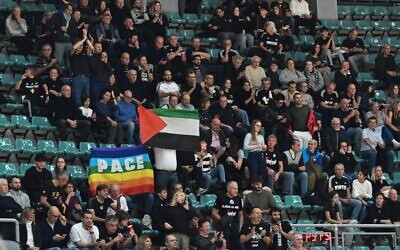 Des manifestants anti-israéliens brandissent des drapeaux palestiniens et une pancarte sur laquelle on peut lire "Carton rouge à Israël" pour protester contre la participation d'Israël à des événements sportifs, à l'extérieur d'un match de basket-ball entre Virtus Bologne et Maccabi Tel Aviv à Bologne, en Italie, le 21 novembre 2025. (Capture d'écran : Il Fatto Quotidiano)