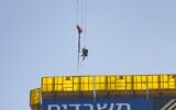 Un adolescent suspendu à une grue, au-dessus d'un immeuble de grande hauteur ,est secouru à l'entrée de Jérusalem, le 24 novembre 2025. (Chaim Goldberg/Flash90)