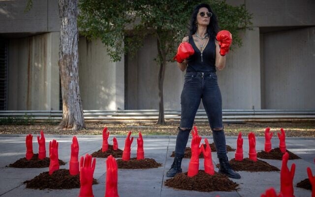 Une femme porte des gants de boxe au milieu de mains rouges symbolisant les femmes assassinées lors d'un happening organisé à l'occasion de la Journée internationale pour l'élimination des violences faites aux femmes devant la Her Academy, un établissement de formation pour les survivantes de la prostitution et des violences sexuelles, à Tel Aviv, le 24 novembre 2025. (Crédit : Miriam Alster/Flash90) Une femme porte des gants de boxe au milieu de mains rouges symbolisant les femmes assassinées lors d'un happening organisé à l'occasion de la Journée internationale pour l'élimination des violences faites aux femmes devant la Her Academy, un établissement de formation pour les survivantes de la prostitution et des violences sexuelles, à Tel Aviv, le 24 novembre 2025. (Crédit : Miriam Alster/Flash90)