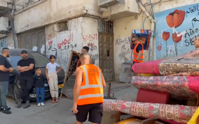 Des déménageurs transportent des meubles et d’autres effets personnels après l'expulsion de deux familles palestiniennes de leurs maisons dans le quartier de Silwan, à Jérusalem-Est, le 9 novembre 2025. (Crédit : Capture d'écran/X, utilisée conformément à la clause 27a de la loi sur le droit d'auteur)