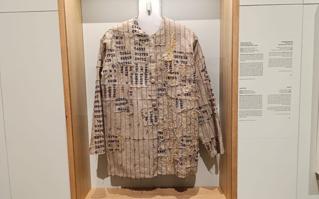 Une interprétation artistique par Shulamit Levin, survivante de l'Holocauste, du manteau aux multiples couleurs de Joseph dans la Bible, réimaginé sous la forme d'une chemise de prisonnier effilochée, marquée de numéros d'identification et de pétales de fleurs. Exposée dans l'exposition "Living Memory" (Mémoire vivante) de Yad Vashem (Crédit : Zev Stub/Times of Israel)