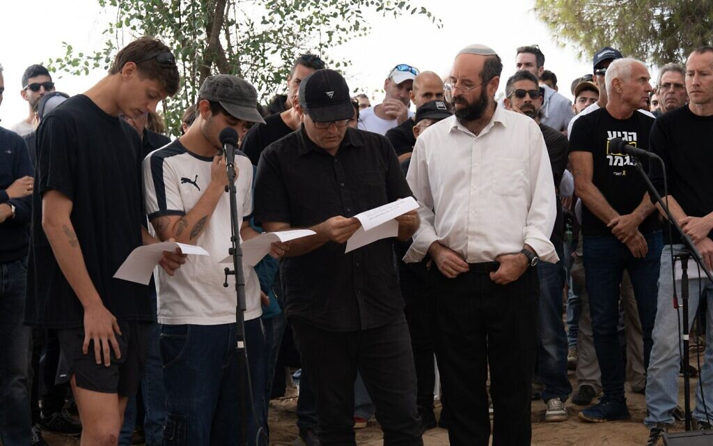Lors des funérailles de Dror Or, ses fils, Yahli et Noam, à l'extrême gauche et au centre, ainsi que son frère, Elad Or, récitant le Kaddish, au kibboutz Beeri, le 30 novembre 2025. (Crédit : Dana Reany/Forum des otages)