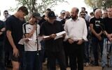 Lors des funérailles de Dror Or, ses fils, Yahli et Noam, à l'extrême gauche et au centre, ainsi que son frère, Elad Or, récitant le Kaddish, au kibboutz Beeri, le 30 novembre 2025. (Crédit : Dana Reany/Forum des otages)