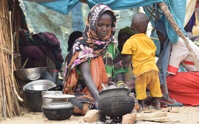 Une réfugiée soudanaise qui a traversé la frontière avec le Tchad prépare un repas dans un abri de fortune dans un camp à Koufroun, près d'Echbara, le 1er mai 2023. (Crédit : Gueipeur Denis Sassou/AFP)