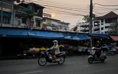 Illustration : Des personnes circulant à moto le long d'une route près d'un marché, dans le centre-ville de Chiang Mai, en Thaïlande, le 7 avril 2023. (Crédit : AFP)
