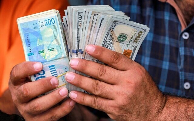 Photo d'Illustration : un homme compte des liasses de billets en shekels israéliens et en dollars américains dans un bureau de change informel à Deir al-Balah, dans le centre de la bande de Gaza, le 2 juillet 2024. (Crédit : Bashar TALEB / AFP) Photo d'Illustration : un homme compte des liasses de billets en shekels israéliens et en dollars américains dans un bureau de change informel à Deir al-Balah, dans le centre de la bande de Gaza, le 2 juillet 2024. (Crédit : Bashar TALEB / AFP)