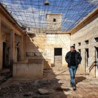 Un habitant passe devant des cellules alors qu’il guide des journalistes visitant le complexe pénitentiaire de Palmyre, anciennement utilisé par le gouvernement Assad renversé, dans la ville du centre syrienne de Palmyre, le 7 février 2025. (Crédit : OMAR HAJ KADOUR/AFP)