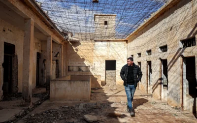 Un habitant passe devant des cellules alors qu’il guide des journalistes visitant le complexe pénitentiaire de Palmyre, anciennement utilisé par le gouvernement Assad renversé, dans la ville du centre syrienne de Palmyre, le 7 février 2025. (Crédit : OMAR HAJ KADOUR/AFP)