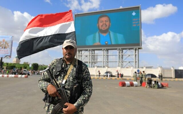 Un membre des forces de sécurité du groupe terroriste des Houthis montant la garde devant un écran géant diffusant le discours du chef Abdel-Malik al-Houthi, à Sanaa, le 19 septembre 2025. (Credit : Mohammed Huwais/AFP)