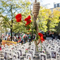 Illustration : un nœud coulant orné de fleurs artificielles à côté de portraits de personnes exécutées par le gouvernement iranien, exposés lors d'une manifestation contre la peine capitale en Iran, dans le centre de Paris, le 11 octobre 2025. (Crédit : Martin LELIEVRE / AFP)