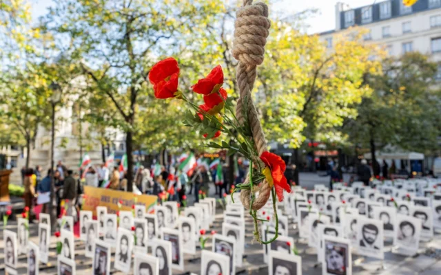 Illustration : un nœud coulant orné de fleurs artificielles à côté de portraits de personnes exécutées par le gouvernement iranien, exposés lors d'une manifestation contre la peine capitale en Iran, dans le centre de Paris, le 11 octobre 2025. (Crédit : Martin LELIEVRE / AFP)