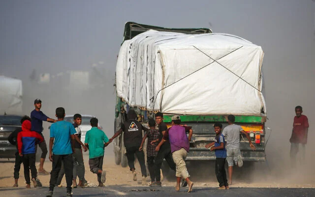 Des Palestiniens déplacés poursuivent des camions qui circulent sur la route de Salah al-Din, dans le centre de la bande de Gaza, près de Deir al-Balah, alors qu’ils tentent d’obtenir de l’aide humanitaire, le 9 novembre 2025. (Eyad Baba/AFP) Des Palestiniens déplacés poursuivent des camions qui circulent sur la route de Salah al-Din, dans le centre de la bande de Gaza, près de Deir al-Balah, alors qu’ils tentent d’obtenir de l’aide humanitaire, le 9 novembre 2025. (Eyad Baba/AFP)