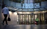Un homme passe devant l'entrée de la BBC à Londres, le 10 novembre 2025. (Crédit : HENRY NICHOLLS / AFP)