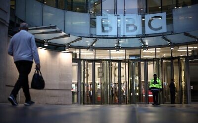 Un homme passe devant l'entrée de la BBC à Londres, le 10 novembre 2025. (Crédit : HENRY NICHOLLS / AFP)