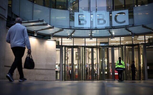 Un homme passe devant l'entrée de la BBC à Londres, le 10 novembre 2025. (Crédit : HENRY NICHOLLS / AFP)