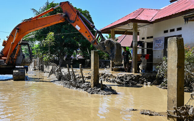 Une pelleteuse dégage la boue autour d'une maison inondée à Meureudu, dans le district de Pidie Jaya, province d'Aceh en Indonésie, le 30 novembre 2025. Le bilan des inondations qui ont frappé l'Indonésie cette semaine s'élève désormais à plus de 500 morts, selon les chiffres de l'agence de gestion des catastrophes.(Crédit : CHAIDEER MAHYUDDIN / AFP)