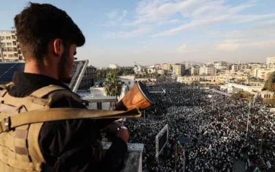 Un membre des forces de sécurité syriennes montant la garde depuis un poste surplombant la foule, lors des célébrations marquant le premier anniversaire de l'offensive éclair menée par les islamistes et qui a finalement renversé le dictateur syrien Bashar el-Assad, dans le centre de Hama, le 5 décembre 2025. (Crédit : Omar Haj Kadour/AFP)