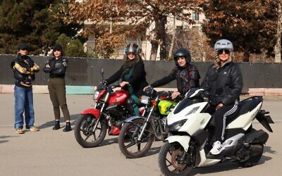 L'instructrice iranienne Maryam Ghelich se tient aux côtés de son élève Narghes alors qu'elles regardent Elham (3e à droite), Leila et Mona, posant sur leurs motos avant leur cours dans un centre de formation au nord de Téhéran, le 7 décembre 2025. (Crédit : ATTA KENARE / AFP)
