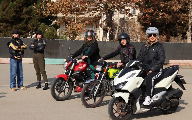 L'instructrice iranienne Maryam Ghelich se tient aux côtés de son élève Narghes alors qu'elles regardent Elham (3e à droite), Leila et Mona, posant sur leurs motos avant leur cours dans un centre de formation au nord de Téhéran, le 7 décembre 2025. (Crédit : ATTA KENARE / AFP) L'instructrice iranienne Maryam Ghelich se tient aux côtés de son élève Narghes alors qu'elles regardent Elham (3e à droite), Leila et Mona, posant sur leurs motos avant leur cours dans un centre de formation au nord de Téhéran, le 7 décembre 2025. (Crédit : ATTA KENARE / AFP)