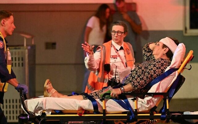 Des secouristes transportent une femme sur une civière vers une ambulance après une fusillade terroriste meurtrière à Bondi Beach, à Sydney, le 14 décembre 2025. (Crédit : Saeed KHAN / AFP) Des secouristes transportent une femme sur une civière vers une ambulance après une fusillade terroriste meurtrière à Bondi Beach, à Sydney, le 14 décembre 2025. (Crédit : Saeed KHAN / AFP)