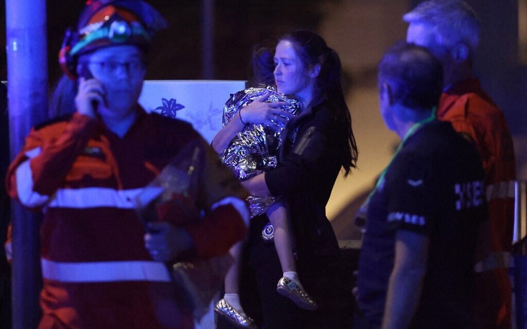 Une femme tenant son enfant dans ses bras après une fusillade lors d'un événement organisé à l'occasion de Hanoukka, à Bondi Beach, à Sydney, le 14 décembre 2025. (Crédit : David Gray/AFP)