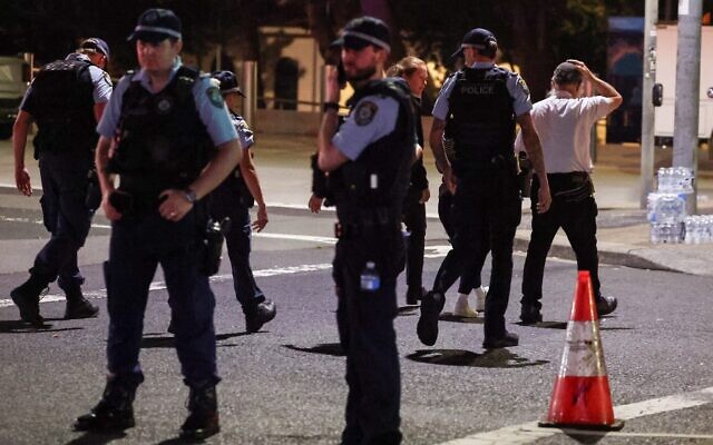 Un membre de la communauté juive réagissant alors qu'il se rend avec la police sur les lieux d'une attaque terroriste, à Bondi Beach, à Sydney, le 14 décembre 2025. (Crédit : David Gray/AFP)