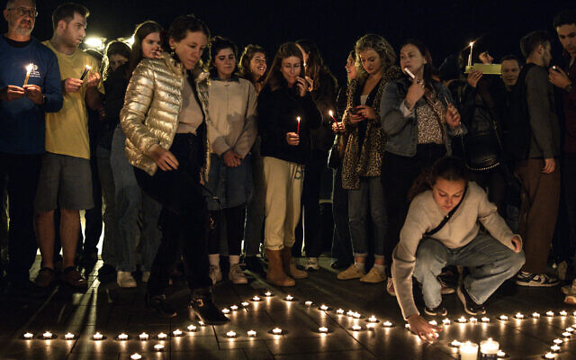 Des Israéliens placent des veilleuses en forme d'étoile de David lors d'une veillée aux chandelles quelques heures après que deux hommes armés ont abattu des personnes rassemblées sur la plage de Bondi en Australie pour la fête juive de Hanoukka, à Tel-Aviv, le 14 décembre 2025. (Crédit : JOHN WESSELS / AFP)