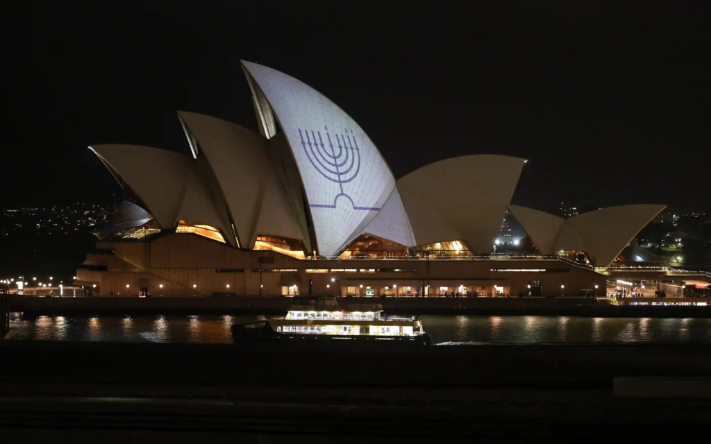 Une hanoukkia est projetée sur les voiles de l'Opéra de Sydney en mémoire des victimes de la fusillade de Bondi Beach, à Sydney, le 15 décembre 2025. (Crédit : DAVID GRAY / AFP)