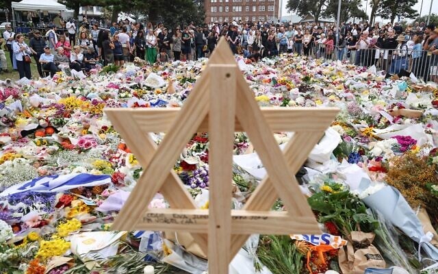 Une étoile de David en bois au milieu des fleurs déposées en hommage aux victimes de l'attentat terroriste perpétré à Bondi Beach pendant la fête de Hanoukka, devant le Bondi Pavilion, à Sydney, le 16 décembre 2025. (Crédit : David Gray/AFP)