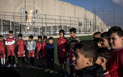Des jeunes Palestiniens déplacés participent à une séance d'entraînement sur le terrain de football du camp de réfugiés d'Aida, à côté de la barrière de sécurité israélienne à l'extérieur de Bethléem, en Cisjordanie, le 16 décembre 2025, quelques semaines après la décision de l'armée israélienne de démolir le terrain. (Crédit : Photo de JOHN WESSELS / AFP)