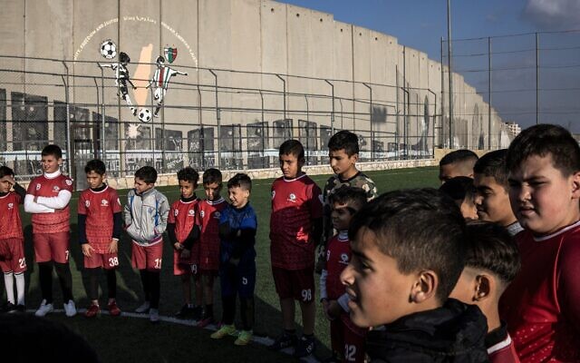 Des jeunes Palestiniens déplacés participent à une séance d'entraînement sur le terrain de football du camp de réfugiés d'Aida, à côté de la barrière de sécurité israélienne à l'extérieur de Bethléem, en Cisjordanie, le 16 décembre 2025, quelques semaines après la décision de l'armée israélienne de démolir le terrain. (Crédit : Photo de JOHN WESSELS / AFP) Des jeunes Palestiniens déplacés participent à une séance d'entraînement sur le terrain de football du camp de réfugiés d'Aida, à côté de la barrière de sécurité israélienne à l'extérieur de Bethléem, en Cisjordanie, le 16 décembre 2025, quelques semaines après la décision de l'armée israélienne de démolir le terrain. (Crédit : Photo de JOHN WESSELS / AFP)