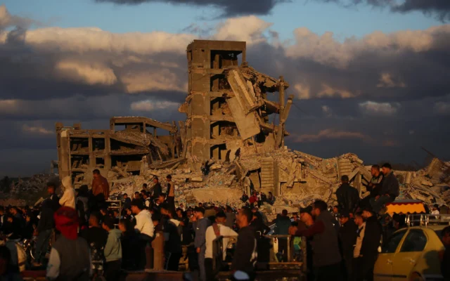 Des Palestiniens déplacés se tiennent à côté de maisons détruites dans le camp de Nuseirat, dans le centre de la bande de Gaza, le 19 décembre 2025. (Crédit : Eyad Baba / AFP) Des Palestiniens déplacés se tiennent à côté de maisons détruites dans le camp de Nuseirat, dans le centre de la bande de Gaza, le 19 décembre 2025. (Crédit : Eyad Baba / AFP)
