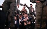 Les forces de sécurité dispersant des Juifs ultra-orthodoxes bloquant une route lors d'une manifestation contre la conscription dans l'armée israélienne, à Bnei Brak, le 22 décembre 2025. (Crédit : Ilia Yefimovich/AFP)