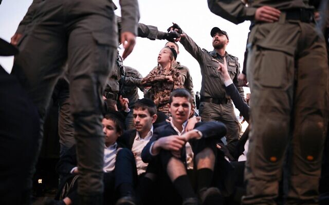 Les forces de sécurité dispersant des Juifs ultra-orthodoxes bloquant une route lors d'une manifestation contre la conscription dans l'armée israélienne, à Bnei Brak, le 22 décembre 2025. (Crédit : Ilia Yefimovich/AFP) Les forces de sécurité dispersant des Juifs ultra-orthodoxes bloquant une route lors d'une manifestation contre la conscription dans l'armée israélienne, à Bnei Brak, le 22 décembre 2025. (Crédit : Ilia Yefimovich/AFP)