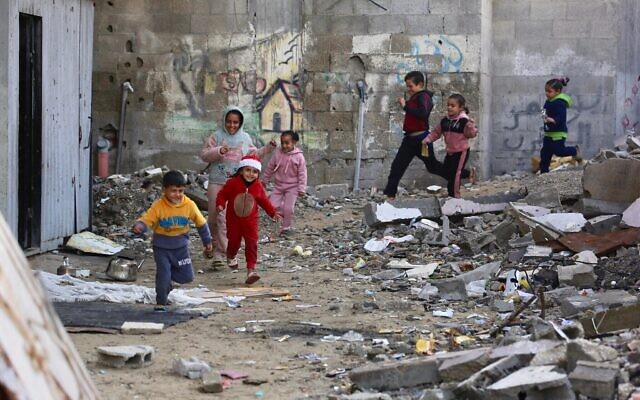 Illustration : Des enfants gazaouis jouent à côté des décombres de bâtiments détruits dans le camp de réfugiés de Jabaliya, dans le nord de la bande de Gaza, le 24 décembre 2025. (Crédit : Bashar Taleb/AFP)