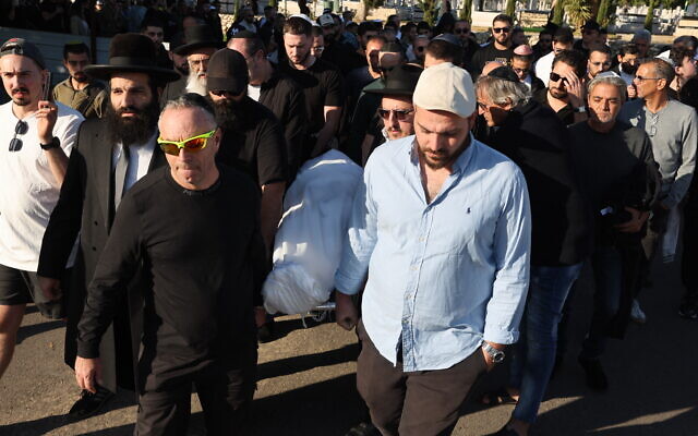 Les proches et amis de Dan Elkayam, 27 ans, ingénieur juif français originaire du Bourget, tué lors de l'attentat terroriste qui a frappé la plage de Bondi en Australie le 14 décembre, pendant la fête juive de Hanoukka, portent son corps lors de ses funérailles au cimetière d'Ashdod, dans le sud d'Israël, le 25 décembre 2025. (Crédit : Jack Guez/AFP)