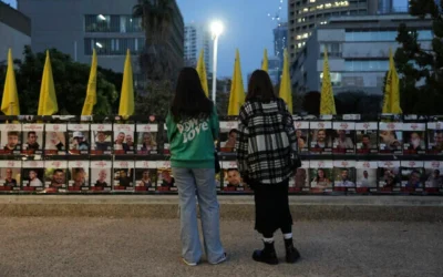 Deux femmes regardent les photos d'otages détenus dans la bande de Gaza, sur une clôture à Tel Aviv, le 15 janvier 2025. (Photo AP/Oded Balilty)