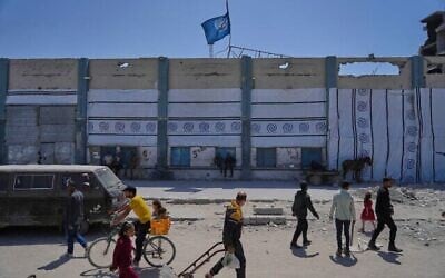 Des Palestiniens marchant à côté du centre de distribution d'aide humanitaire fermé de l'UNRWA, l'agence des Nations unies qui vient en aide aux réfugiés palestiniens à Jabaliya, dans la bande de Gaza, le 29 avril 2025. (Crédit : Jehad Alshrafi/AP)