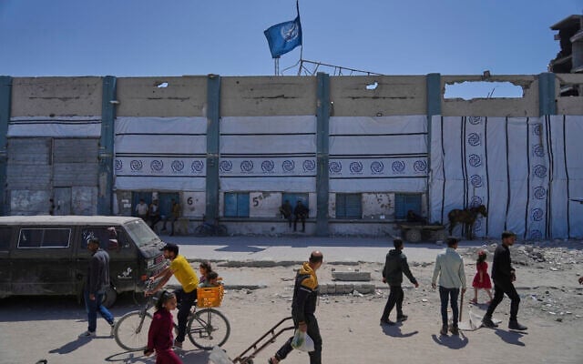 Des Palestiniens marchant à côté du centre de distribution d'aide humanitaire fermé de l'UNRWA, l'agence des Nations unies qui vient en aide aux réfugiés palestiniens à Jabaliya, dans la bande de Gaza, le 29 avril 2025. (Crédit : Jehad Alshrafi/AP)