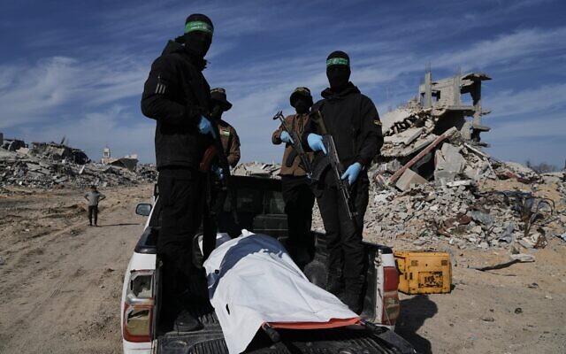 Des terroristes du Jihad islamique palestinien et du Hamas transportant un sac mortuaire blanc qui contiendrait la dépouille d'un otage, à Beit Lahiya, au nord de la bande de Gaza, le 3 décembre 2025. (Crédit : Jehad Alshrafi/AP)
