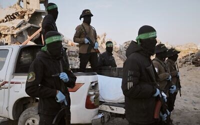 Des terroristes armés masqués du Jihad islamique palestinien et du Hamas remettant à la Croix-Rouge un sac mortuaire contenant vraisemblablement la dépouille d'un otage, qui sera transférée aux autorités israéliennes, à Beit Lahiya, dans le nord de la bande de Gaza, le 3 décembre 2025. (Crédit : Jehad Alshrafi/AP)