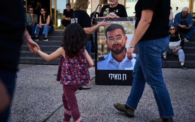 Un homme tenant une affiche de Ran Gvili, tué lors d'un combat contre le Hamas le 7 octobre 2023 et dont le corps est retenu à Gaza depuis lors, lors d'un rassemblement appelant à son retour, à Tel Aviv, le 5 décembre 2025. (Crédit : Oded Balilty/AP)