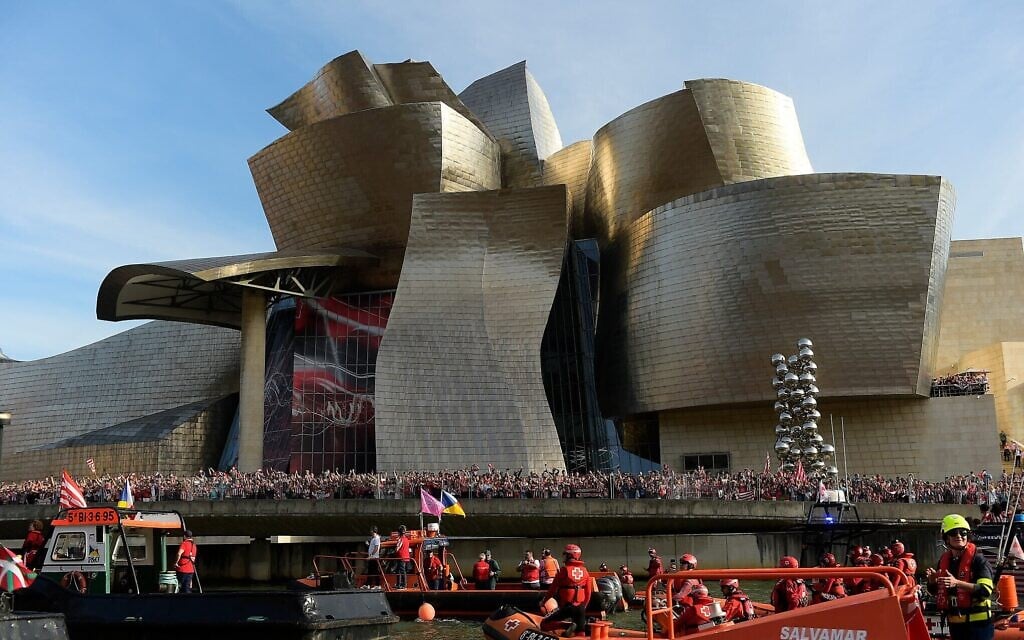 Les supporters de l'Athletic Bilbao attendent devant le musée Guggenheim alors que des bateaux passent devant eux, avant les célébrations de l'équipe sur l'estuaire du Nervion, à Bilbao, en Espagne, le 11 avril 2024. (Crédit : AP Photo/Alvaro Barrientos, Document)